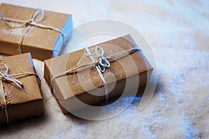 Handmade gift boxes from craft paper over snowy wooden table in blue light.