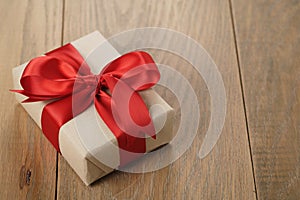 Handmade gift brown paper box with red ribbon bow on wood table