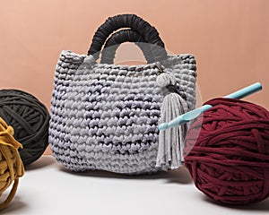 Handmade gray and black bag made with zpagetti yarn next to colored cloth balls