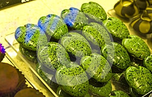 Handmade green candies in the form of monstera leafs on a show-window in shop. Tasty sweets. Supermarket, cafe. Unusual form.