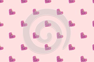 Handmade heart made of purple beads pattern on a pink background.