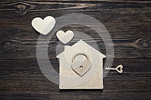 Handmade home symbol with lock-heart and key on wooden background with copy space.