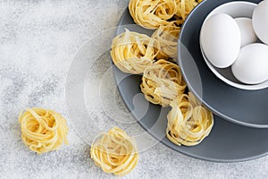 Handmade italian pasta - tagliatelle  with eggs on grey floury background