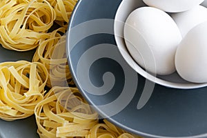 Handmade italian pasta - tagliatelle  with eggs on grey floury background