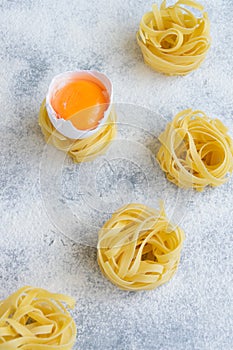 Handmade italian pasta - tagliatelle  with eggs on grey floury background