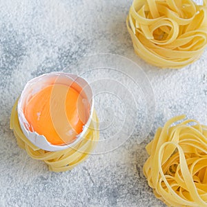 Handmade italian pasta - tagliatelle  with eggs on grey floury background