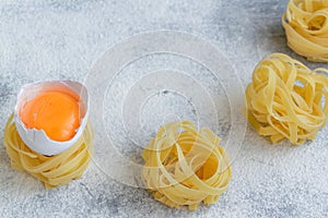 Handmade italian pasta - tagliatelle  with eggs on grey floury background