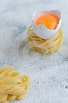 Handmade italian pasta - tagliatelle  with eggs on grey floury background