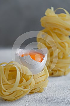 Handmade italian pasta - tagliatelle  with eggs on grey floury background