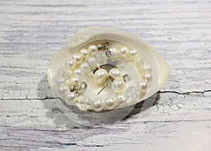 Handmade jewelry made of pearls and silver in the shell on a light background.