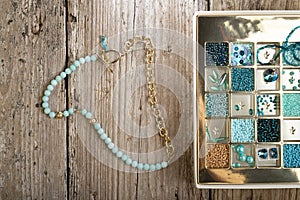 Handmade jewelry necklace  and different azure beads and chrystals in box around old style wooden background. close up