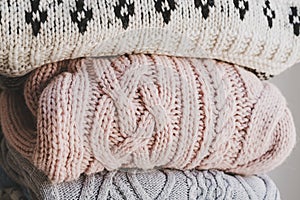 Handmade knitted sweaters. Pile of warm knitted jumpers