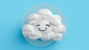 Handmade knitted toy smiling cloud on a blue background, top view