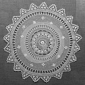 Handmade lace on black background. Macrame fabric lace doily. Crocheted white lace decorative napkin