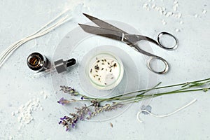Handmade lavender scented candle with essential oil, flowers, wax, wicks, and scissors, flat lay, overhead shot