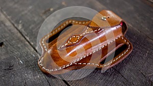 Handmade Leather Pancake Style Swiss Army Knife Sheath on wooden background. Stitching by hand.