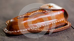 Handmade Leather Pancake Style Swiss Army Knife Sheath on wooden background. Stitching by hand.