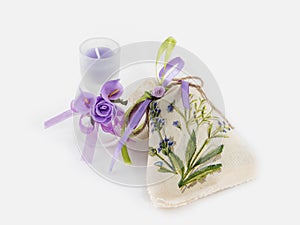 Handmade Linen sack and aroma candle in glass decorated with artificial flowers on white background