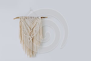 Handmade macrame decoration hanging on a white empty wall.