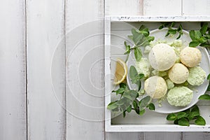 Handmade mint bath bombs with fresh herbs in white tray