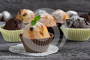 Handmade muffins with a leaf of mint on a wooden table