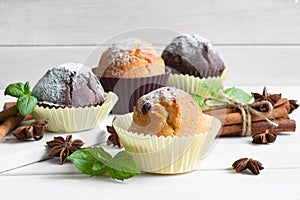 Handmade muffins with a leaf of mint on a wooden table with cinnamon and star anise