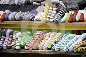 Handmade multi-colored knitted socks and slippers lie on the window of the street market