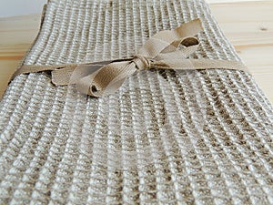 Handmade natural linen bath towel with waffle texture on wooden background. Gift.