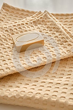 Handmade natural olive soap lies on a natural muslin towel. Composition in beige.
