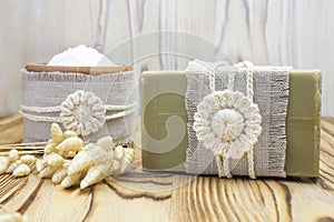 Handmade, natural organic olive oil soap and cosmetic salt on linen and wooden background. Spa bath accessories, feminine care pro