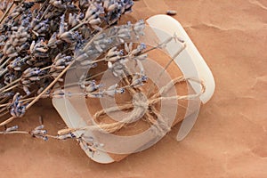 Handmade natural soap bar with dry lavender flowers on craft paper background.