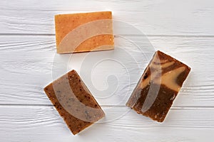 Handmade natural soap blocks on white wooden background.