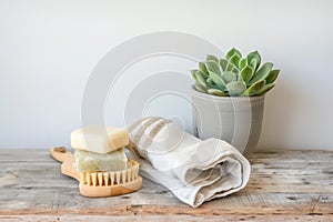 Handmade natural soaps, succulent in terracotta, cotton towels and wooden brush on wooden table