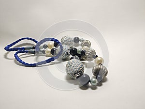 handmade necklace, blue string, lots of beads of different shapes and colors, there are white beads