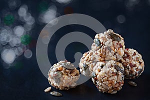 Handmade no bake organic seeds nuts vegan almond energy balls on black slate of tile with light white silver bokeh