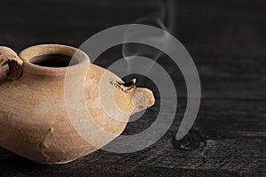 A Handmade Oil Lamp with a Smoldering Wick photo