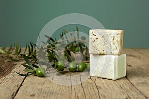 Handmade olive soap with olive branch on wooden table.