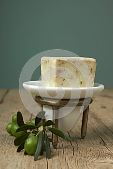 Handmade olive soap with olive branch on wooden table.