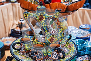 handmade oriental Uzbek teapot jug with mugs hand-painted with traditional Asian patterns in souvenir shop in Uzbekistan