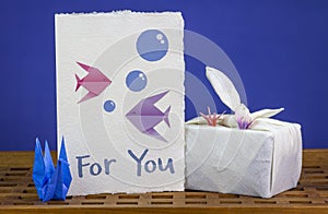 Handmade origami swans, card with origami fish together with Furoshiki fabric wrapped gift photo