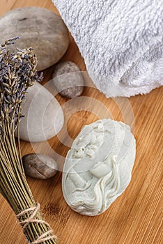 Handmade ornamental soaps with lavender bunch and stones on wooden board, product of cosmetics or body care