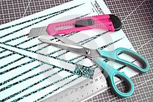 Handmade paper bead templates of green colored floral patterns lying on a cutting mat with pink craft knife and a