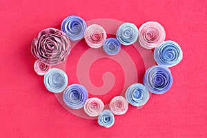 Handmade paper flowers heart frame on a pink background. Beautiful Pink, lilac, purple paper roses in the form of heart. Greeting