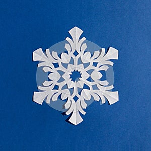 Handmade paper snowflake on blue background