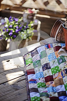 Handmade patchwork blanket on wooden table with spring flowers on background