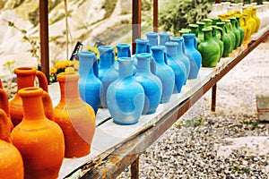 Handmade pitchers of different colors on a wooden table