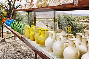 Handmade pitchers of different colors on a wooden table