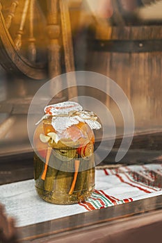 Handmade preserved tomatos in glass jar close up. Blurred vintage background behind glass