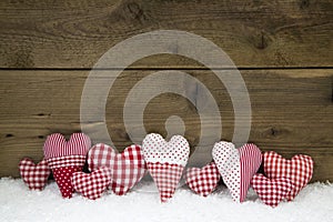 Handmade red white checked hearts on a wooden christmas background.