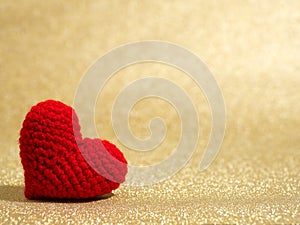 Handmade red yarn heart on gold abstract background. Copy space for text, Valentines day, love concept and love background.